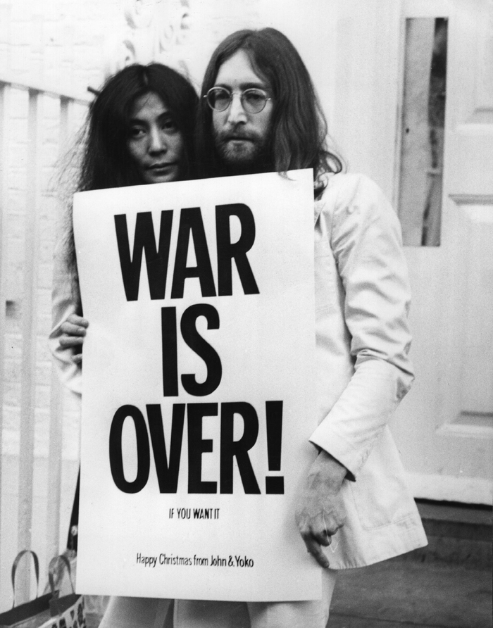 Yoko Ono & John Lennon holding an original WAR IS OVER! poster.