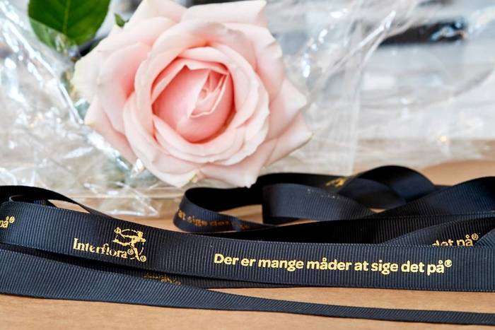 Ribbon with the Interflora logo and the slogan (“There are many ways to say it”) set in Omnes Bold.