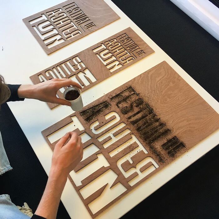 The festival logo – with  caps from various weights of Kayak, featuring  and  – cut in plywood in different sizes and used as stencil for a handmade eroded look.