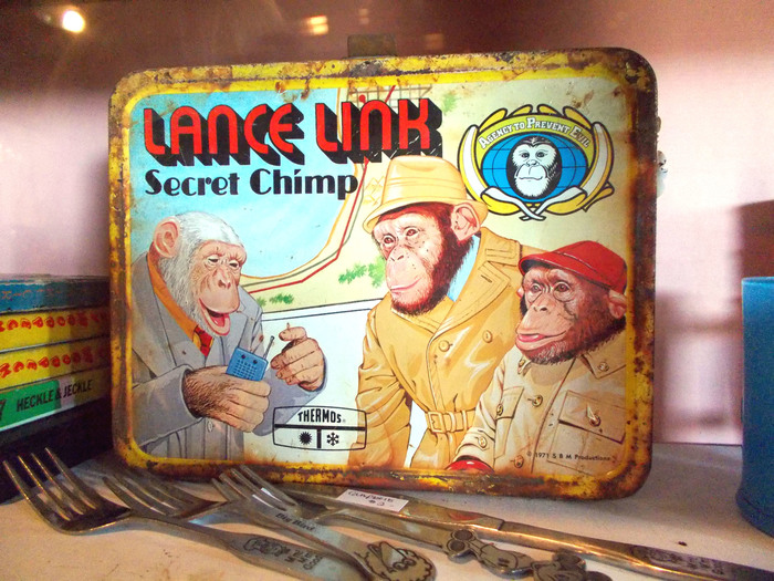 Among the accompanying merchandise was a metal lunch box produced by Thermos (1971). Here, the “Lance Link” wordmark uses  Shaded (Photo-Lettering, 1970). This precursor to  (1975) was drawn by Ed Benguiat, who also helped to develop the title graphic for Planet of the Apes in 1968. [House Industries] “Secret Chimp” is set in . Link is shown together with Mata Hairi and his boss, Commander Darwin.