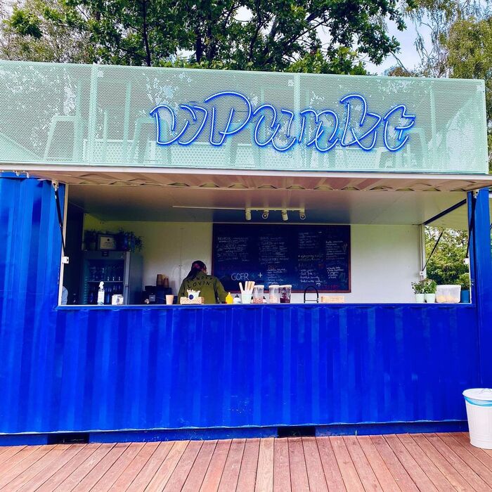 The kitchen and bar are housed in a container, with seating areas in front and on top of it.