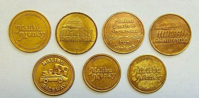 Coins for the Malibu Grand Prix and the Malibu Castle & Showboat, additionally featuring  and . From Preston Lerner’s article:



Ron [Carpenter] came up with the idea for buying video games so they’d be spending money while they were waiting to drive the cars,” [Jack] Long says. Looking back, this seems like a no-brainer. But you’ve got to remember that video games were in their infancy, and arcades for computer games hardly existed. Cameron bought so many coin-operated arcade games that Warner Communications, which owned Atari, acquired Malibu Grand Prix in 1977 and embarked on a $30 million expansion.
