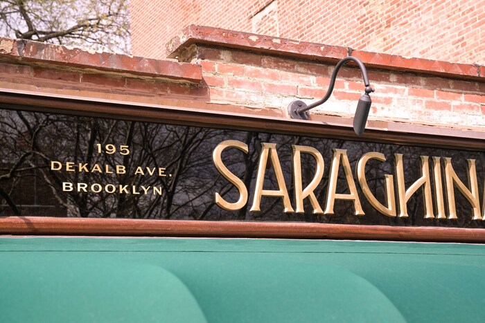 Shop sign in the Saraghina typeface, with Sweet Gothic for the address