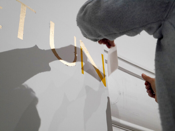 Philip Surey applies gold leaves onto the painted letters.