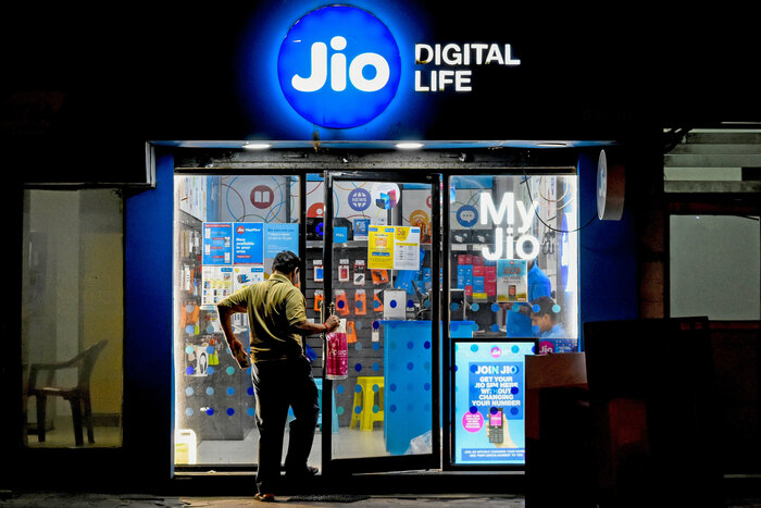 A shop front at night, with an illuminated sign featuring the Jio logo