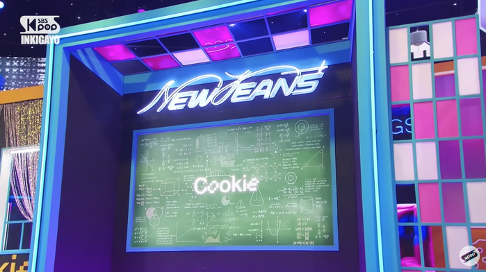 Screenshot of NewJeans’ stage design for their performance of “Cookie” in Inkigayo (SBS). It features one of their logos affixed with neon lights.