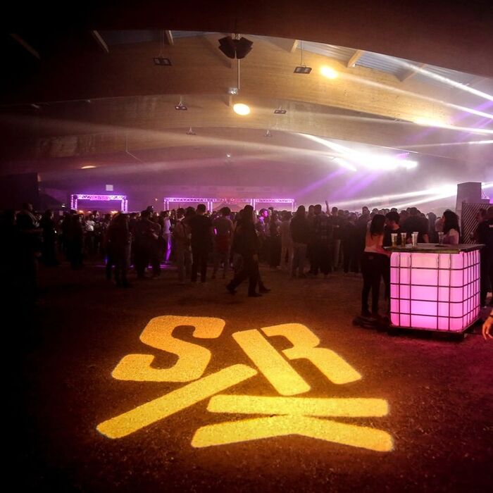 The Sirk logo in jumbled letters from Tempel Softland, projected onto the floor of Dijon’s Boulodrome