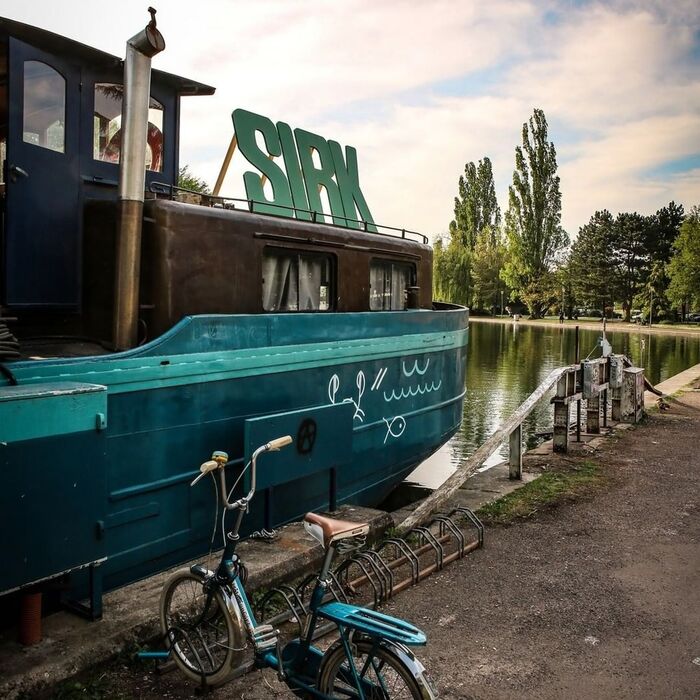 The Sirk logo in wooden letters welcome the visitors of the Péniche Cancale, a moored barge in Dijon’s Port du Canal