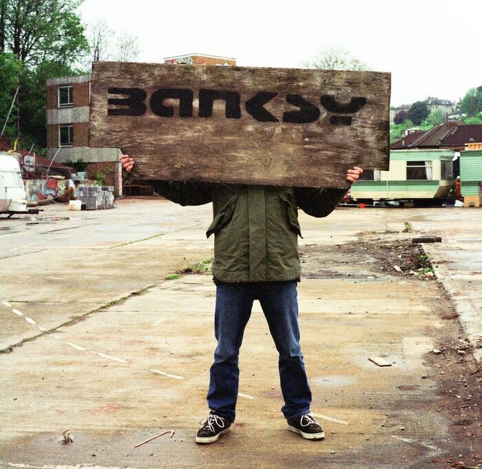 An alleged photo of the elusive Banksy holding the artist’s trademark stencil signature which is based on Stop, with horizontal stretching. The a seen here seems to have been refined over time, being either a custom modification of Stop's C or D, or perhaps loosely based on another font entirely, such as the similar Motter Tektura.