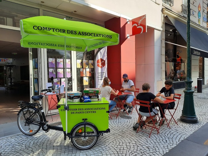 Dapifer in all caps for the umbrella and cargo trike of the Comptoir des Associations, as well as for the white banner in the background