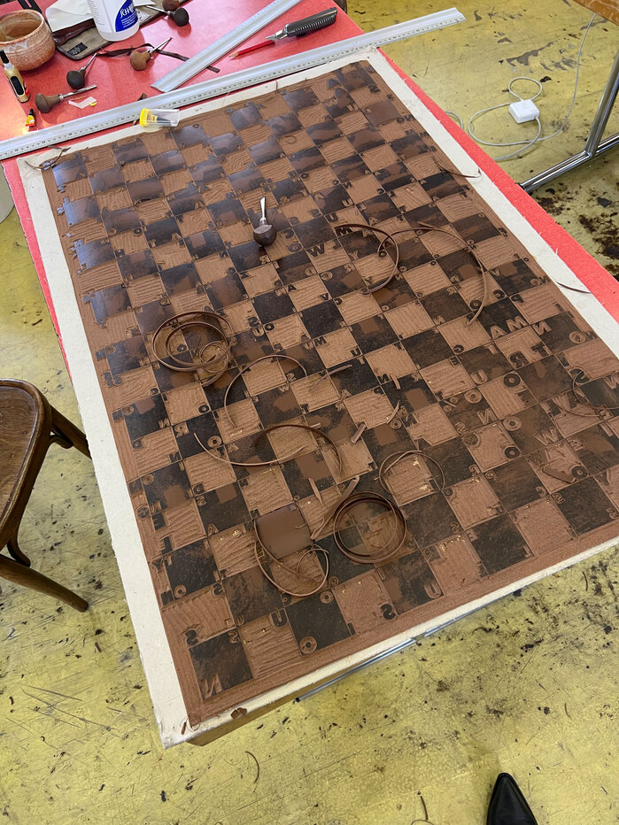 Process of cutting the linoleum for printing. Though all the lines of the checkerboard are straight, they already appear bent.