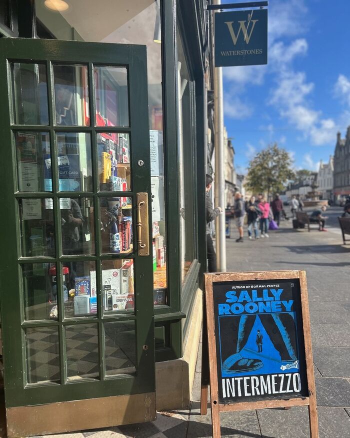 The sign at this book shop features a magnificent rendering of the book jacket and its typography in chalk. Due to the medium of the blackboard, black and white are reversed.