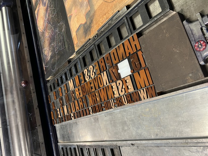 Physical composition of Didot Plakat in 6 Cicero and 10 Cicero. The light brown characters are laser-cut replacements from MDF, the white em-dash is cut from white plastic.