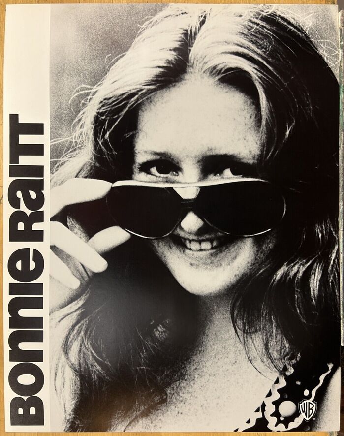 Blues rocker Bonnie Raitt looks over these Warner/Reprise posters. She made her debut on WB in 1971.
