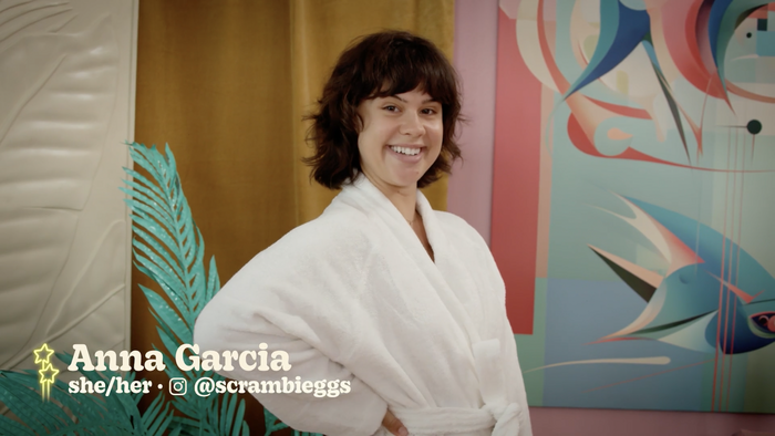 Screenshot from Season 1, Episode 1, picturing Anna Garcia. The text reads “Anna Garcia, she/her, @scrambieggs”, set in Decoy