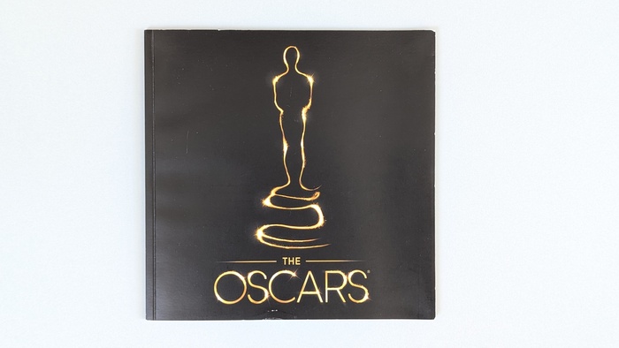 Cover of the official program for the 85th Academy Awards: semi-matte black finish with bronze foil stamping featuring the stylized Oscar statuette