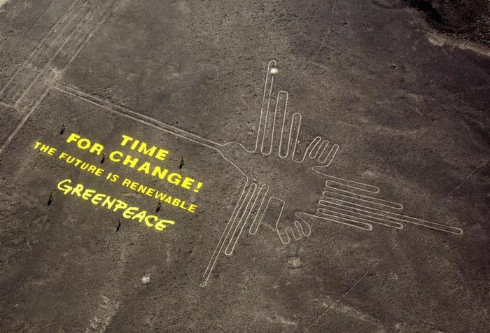 Greenpeace activists stand next to massive letters delivering their message next to the hummingbird geoglyph in Nazca, Peru.