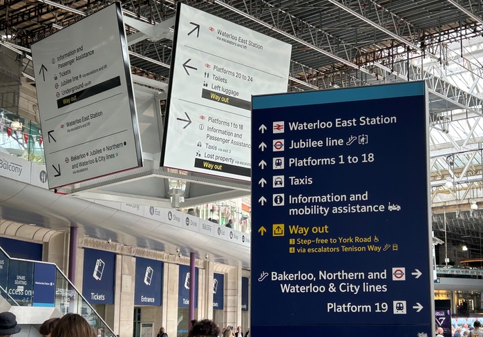 Photograph taken at Waterloo Station on 29 May 2025; the new standard Rail Alphabet 2 is used for the big signs in the background, while the previous standard Brunel is still used for other signage (at the time of writing)