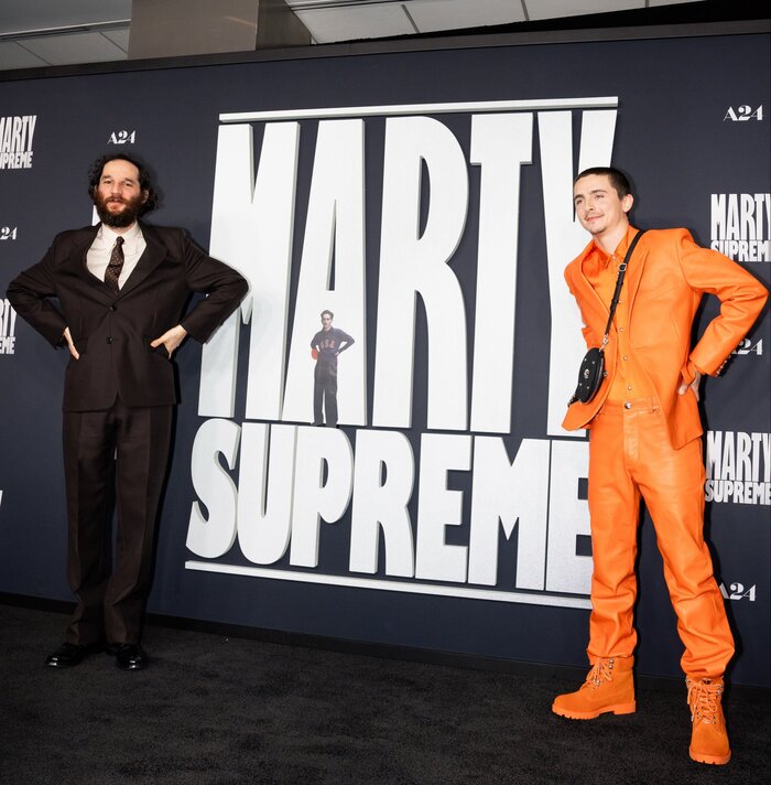 Timothée and Josh Safdie imitating the Marty Mauser pose at the Marty Supreme black carpet in Los Angeles.
