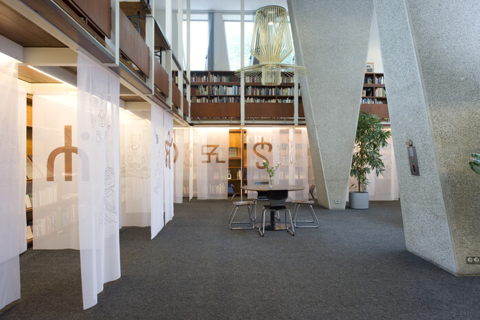The view when entering Alphabetum in The Hague. The publicly accessible library invites visitors to read books, have a coffee, or discuss language with others. Its brutalist yet warm architecture makes every visit to Alphabetum an enriching experience.