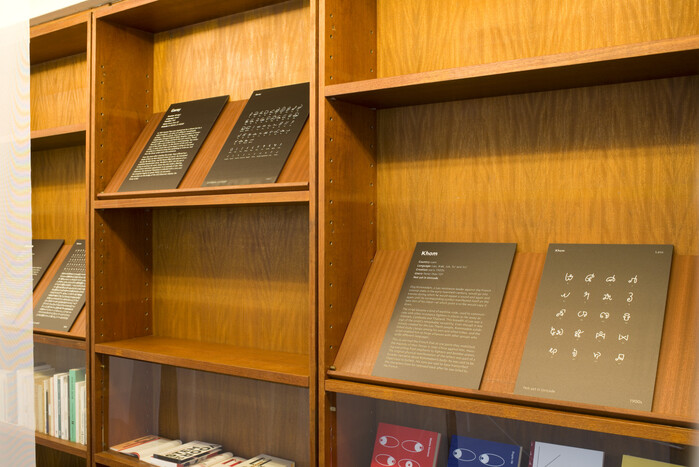 Behind the flags, each writing system is featured on two black A3 panels. On the left, the text and information provided by Tim Brookes; on the right, an example or the full set of glyphs.