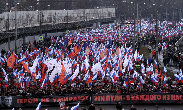 Ralliers carry a banner reading “Heroes never die — these bullets are in each of us”.