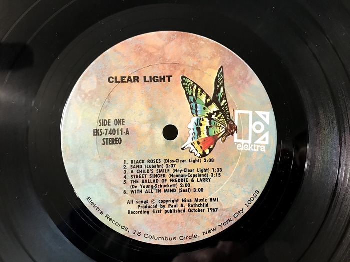 Label for Clear Light’s 1967 self-titled album (circa 1970–1973 reissue). This label design, which features a butterfly carrying the E by its stem (alongside a 7″ design featuring a caterpillar), was first used in August of 1970 on Josh White's The Best of… album.

Band name set in  (ATF; 1904–1913). Disc side indicator, catalog number and “STEREO” set in  Condensed (Ludwig &amp; Mayer; 1929). Track list and credits set in  (/; 1939), a copy of , here with its distinctive two-story a. Address info is set in  (regular; Linotype; 1959).