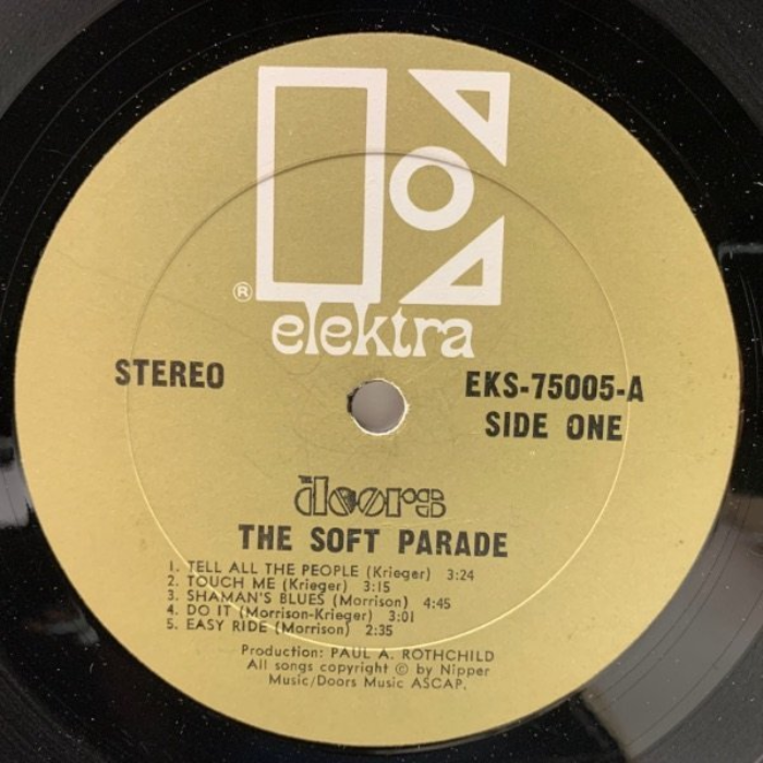 Label for The Doors’ 1969 album The Soft Parade. This label design, as well as the logo, was first used in March of 1966 on Phil Ochs’ In Concert live album.

Catalog number and disc side indicator, “STEREO,” and album title set in  (ATF; 1906) [edit: or rather  (), see comments]. Track list and credits set in  (bold; Intertype; 1930-1946). Band logo is a custom-made sort.