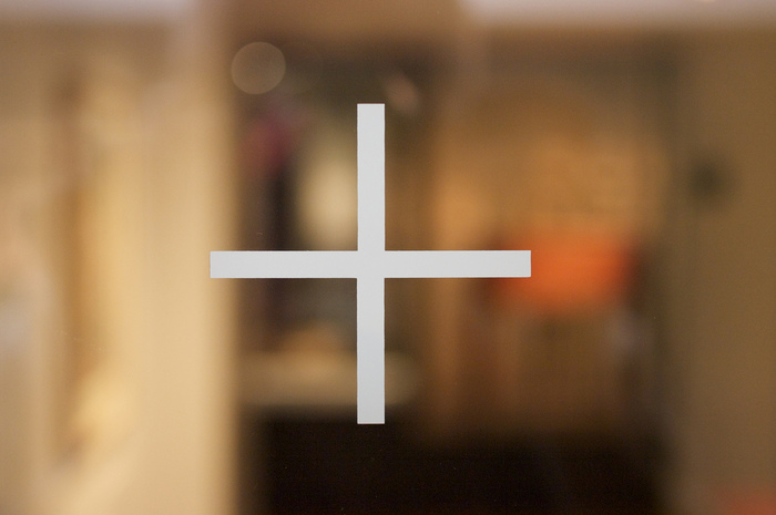 Manifestations on the glass panels and doors are the &lsquo;+&rsquo; in Gill Sans Light from the logo used as a kind of shorthand.