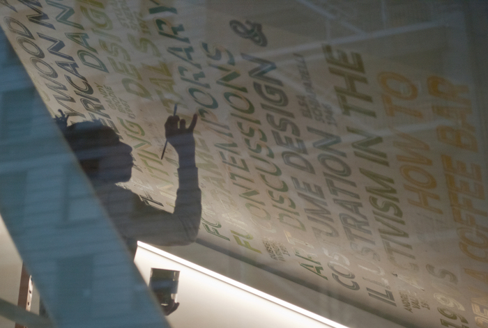 A craftsperson installs part of the hand-painted University Center ticker at dusk.