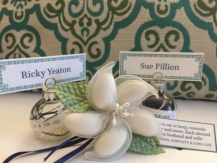 Name holders with sugared almond favors. All pictured are designed, printed and put together by us. In the baubles are peacock feathers, since that is our theme – based on our gemstones, sapphire and emerald. The females features the eye of the feather in the bauble.