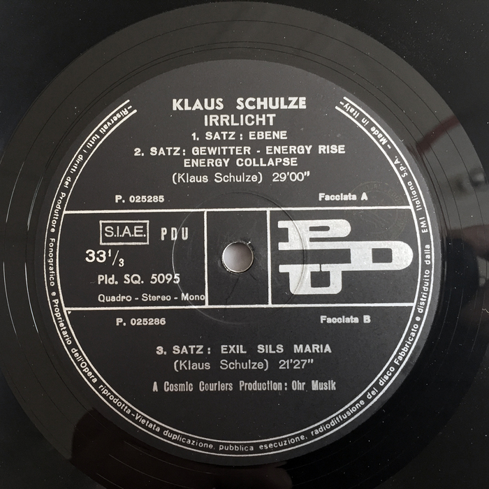 The record label on the A side uses a mix of different sans serif typefaces for information in a more classic look than the rest of the album, including Semplicità Nera (for “Klaus Schulze” — the asymmetrical ‘U’ is the giveaway) and Cairoli, Nebiolo’s version of the German grotesque series best known as Aurora-Grotesk. As the record was produced in Italy, Mr. Schulze was probably not involved in the design of this label, and the record manufacturer simply used what was common, and at hand. The labels of the original release on Ohr show a human ear — “macht auf das [Ohr]” (“open up the ear”), in tightly spaced Helvetica.