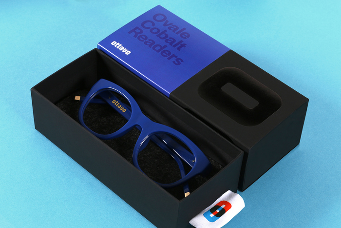 Mucca “designed the packaging with […] the credo that form follows function: a belly band allows a single box to be used for many combinations of lens powers, shapes, and colors; and the tag on the glasses sleeve doubles as a pull to upon the box.”