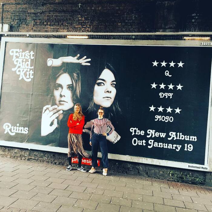 Swedish duo in front of advert in Shoreditch, London