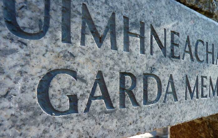 Detail showing the carved dual-language granite plinth leading into the memorial garden.