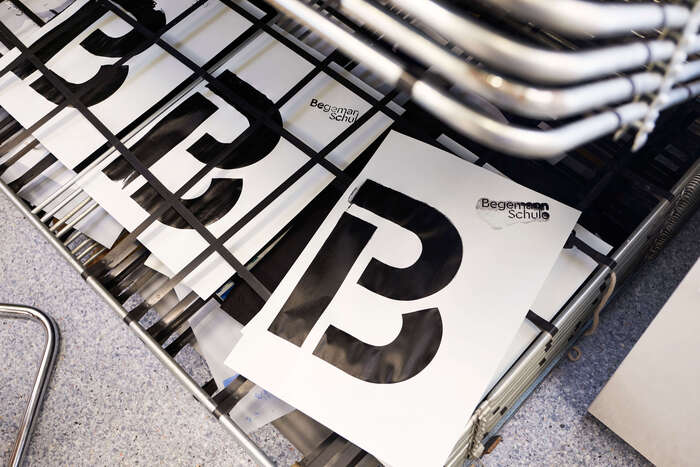 The single-letter logo variant, screen printed at the school’s workshop.
