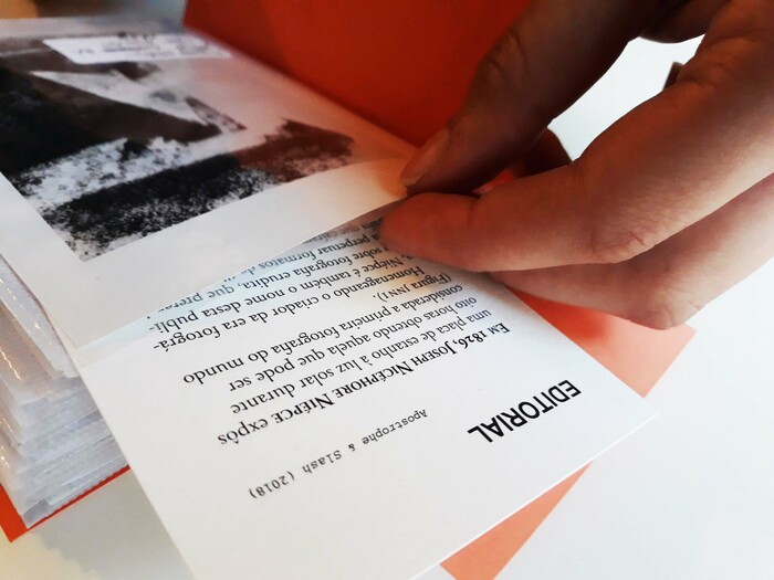 An observer that is really interested in seeing the whole photograph must remove it from the bag. By doing that, articles about the photographer as well as them biography will show up behind the photos, turning the observers into potential readers.